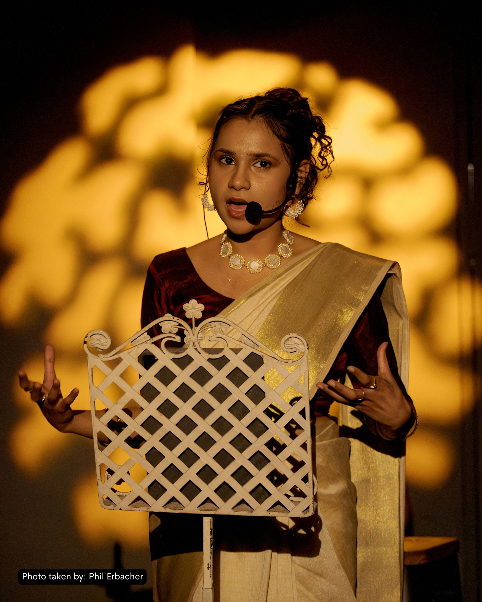 Production photo from And What Will People Say? — Kersh in mid-Bharatanatyam pose under deep amber stage light, audience-close composition.